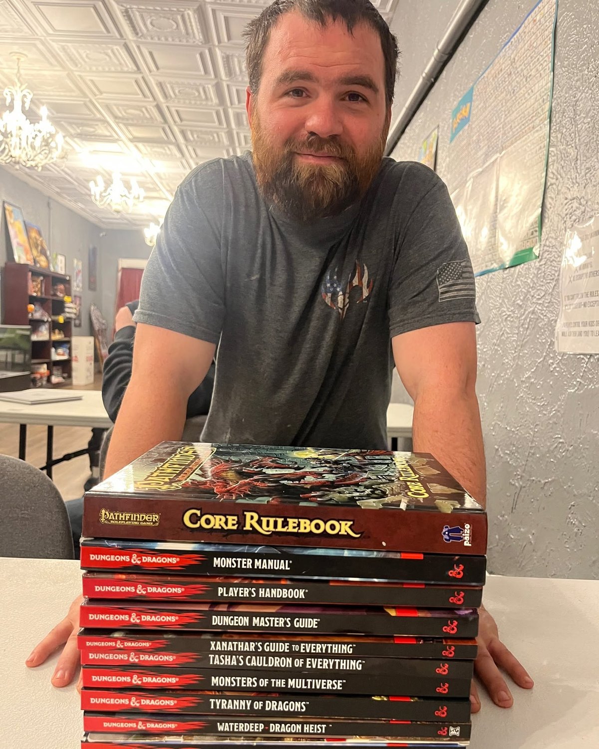 Casey, a Dungeon Master at Checkpoint Gaming, with his stack of rulebooks